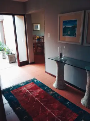 a living room with a table and a red rug at Pecanwood Haven Hartbeesport Dam in Hartbeespoort