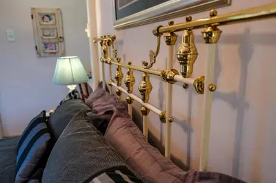 a gold headboard of a bed with pillows and a lamp at Art Gallery Guest House in Haenertsburg