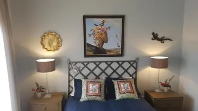 a bedroom with a bed with blue sheets and two lamps at Art Gallery Guest House in Haenertsburg