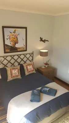 a bedroom with a large bed and a picture on the wall at Art Gallery Guest House in Haenertsburg