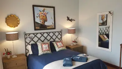 a bedroom with a blue bed and two night stands at Art Gallery Guest House in Haenertsburg