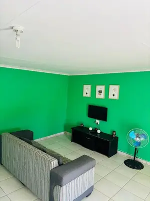 a living room with a couch and a green wall at Cozy Hideout near Kruger in Hectorspruit