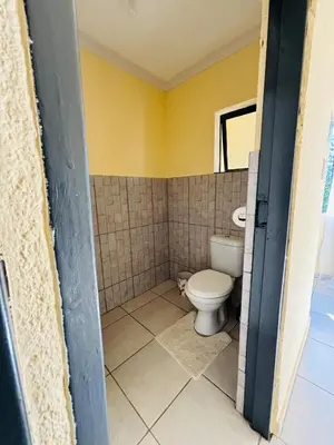 a bathroom with a toilet and a yellow wall at Cozy Hideout near Kruger in Hectorspruit
