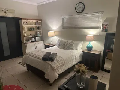 a bedroom with a bed and a clock on the wall at The Mush Room in Centurion