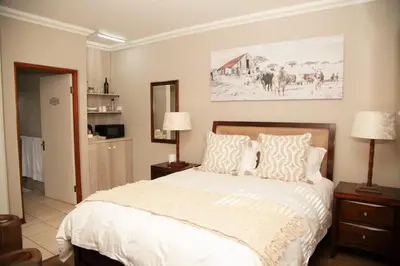 a bedroom with a large white bed with two lamps at Pine & Pebble in Centurion