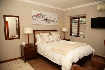 a bedroom with a bed and a mirror and a television at Pine & Pebble in Centurion