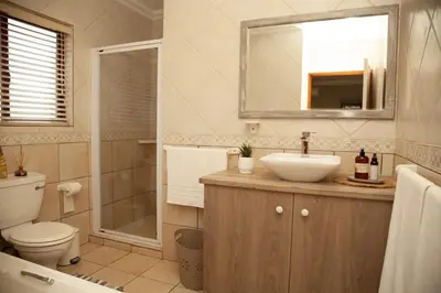 a bathroom with a sink and a toilet and a mirror at Pine & Pebble in Centurion