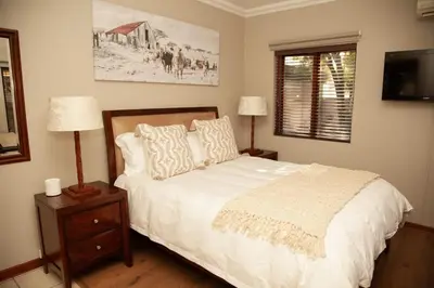 a bedroom with a white bed with two lamps and a window at Pine & Pebble in Centurion