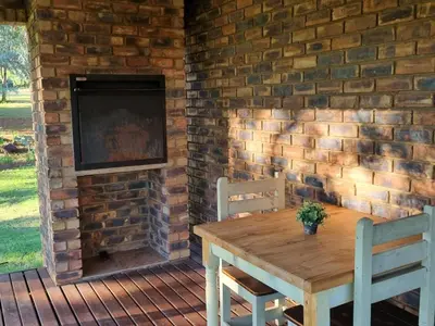a wooden table and chairs in front of a brick fireplace at Villa Rosa Guest Farm in Eersbewoond