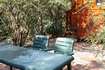 a table and two chairs sitting next to a house at Lerato Bush Lodge in Pretoria