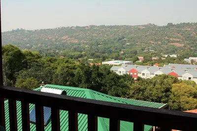 a view of a town from a balcony with a green roof at Lerato Bush Lodge in Pretoria