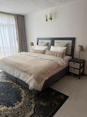 a bedroom with a large bed and a window at Cosy flat with garden near Loftus & embassies in Pretoria