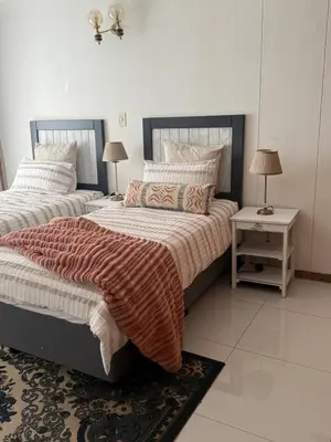 a bedroom with two beds and a table with two lamps at Cosy flat with garden near Loftus & embassies in Pretoria