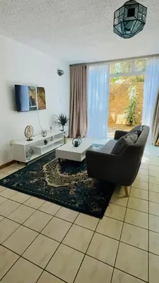 a living room with a couch and a table at Cosy flat with garden near Loftus & embassies in Pretoria