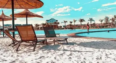 two chairs and an umbrella on a beach with a pool at The Blyde Lagoon apartment in Pretoria