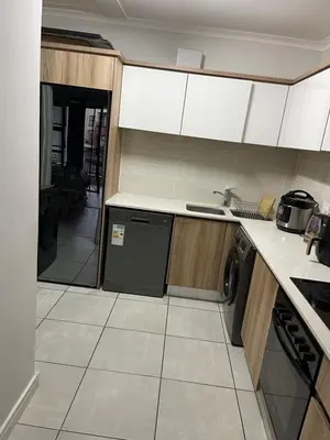 a kitchen with white cabinets and a black dishwasher at The Blyde Lagoon apartment in Pretoria
