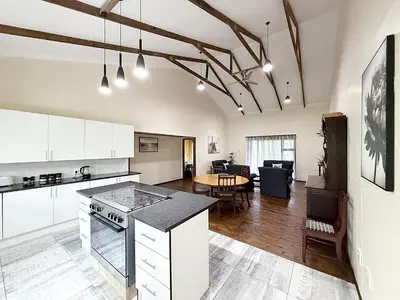 a kitchen with white cabinets and a table in a room at Vulture Suite Hippo Waterfront Lodge in Nelspruit
