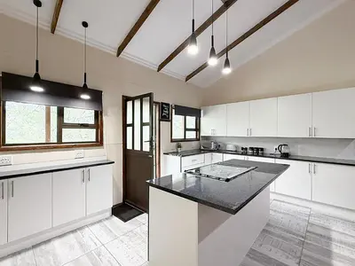 a large kitchen with white cabinets and a black counter top at Vulture Suite Hippo Waterfront Lodge in Nelspruit