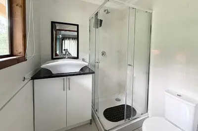 a white bathroom with a shower and a sink at Vulture Suite Hippo Waterfront Lodge in Nelspruit