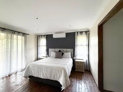a bedroom with a bed with white sheets and windows at Vulture Suite Hippo Waterfront Lodge in Nelspruit