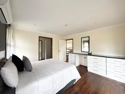 a white bedroom with a large white bed and cabinets at Vulture Suite Hippo Waterfront Lodge in Nelspruit