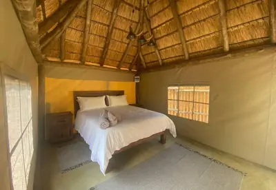 a bedroom with a bed in a room with windows at Vlakvark Tented Camp in Bela-Bela