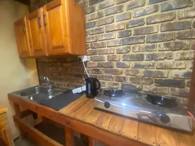 a kitchen counter with a stove and a brick wall at Vlakvark Tented Camp in Bela-Bela
