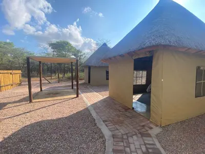 a building with a thatched roof with a playground at Vlakvark Tented Camp in Bela-Bela