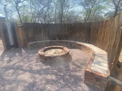 a fire pit in a backyard with a fence at Vlakvark Tented Camp in Bela-Bela