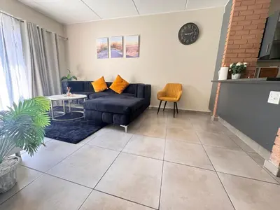 a living room with a couch and a table at Waterfall Garden Unit in Midrand
