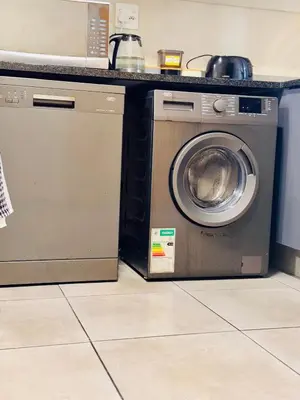 a washing machine in a kitchen next to a microwave at Waterfall Garden Unit in Midrand