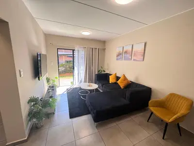a living room with a black couch and a table at Waterfall Garden Unit in Midrand