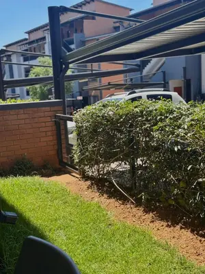 a hedge in front of a building with a car at Waterfall Garden Unit in Midrand