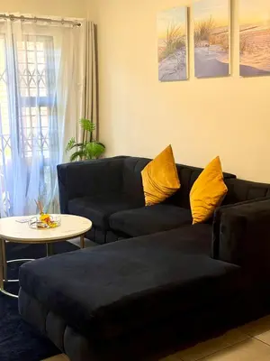 a living room with a black couch and a table at Waterfall Garden Unit in Midrand