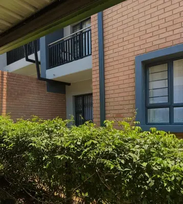 a brick building with a balcony and a bush at Waterfall Garden Unit in Midrand