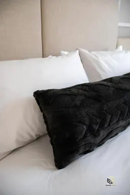 a black pillow on a bed with white pillows at Ezomdabu Guesthouse in Pretoria