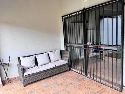 a couch sitting on a patio next to a gate at Bouleigh in Kempton Park