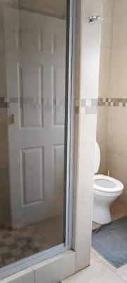a bathroom with a toilet and a glass shower door at Bouleigh in Kempton Park