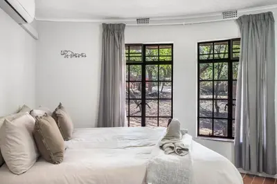 a bedroom with a large white bed with windows at The ChaBo Lodge in Marloth Park