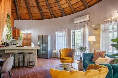 a living room with a blue couch and a kitchen at The ChaBo Lodge in Marloth Park