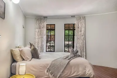 a bedroom with a large bed and two windows at The ChaBo Lodge in Marloth Park
