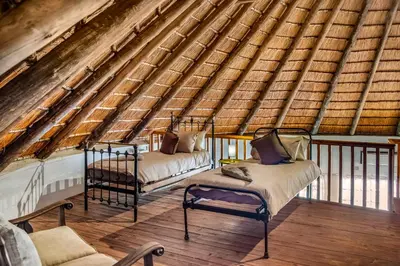 a attic room with two beds and a chair at The ChaBo Lodge in Marloth Park