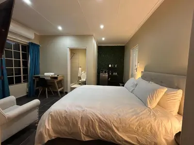 a bedroom with a large white bed and a desk at Hippo Zwartkop Suites in Centurion