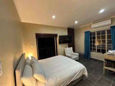 a bedroom with a bed and a desk and a television at Hippo Zwartkop Suites in Centurion