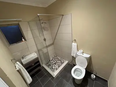a bathroom with a shower and a toilet at Hippo Zwartkop Suites in Centurion