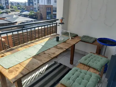 a balcony with a wooden table and green chairs at The Blyde Taffys Place in Pretoria
