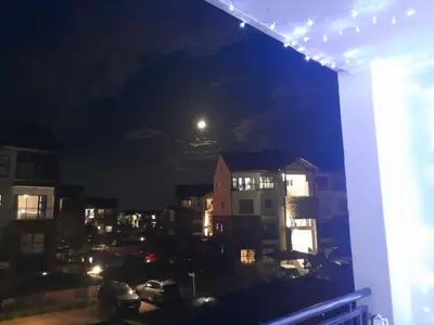 a view of a city at night with a full moon at The Blyde Taffys Place in Pretoria