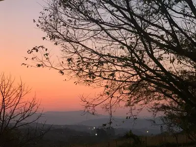 a sunset in the mountains with trees in the foreground at Green Door Cottage