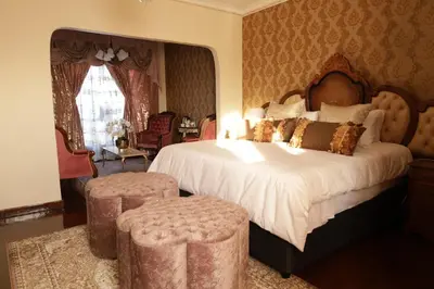a bedroom with a large bed with two stools in it at GBL Reine Chateau in Polokwane