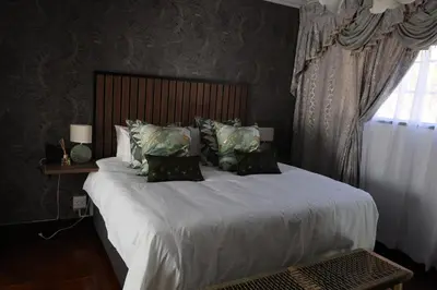 a bedroom with a large bed with white sheets and pillows at GBL Reine Chateau in Polokwane